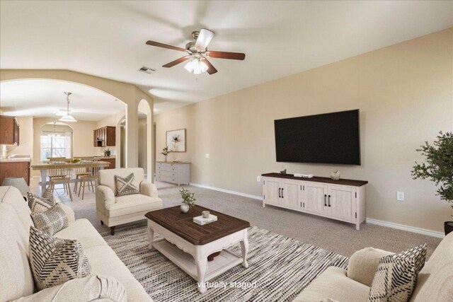 12900 Noche Clara Dr, Del Valle, TX 78617 - living room with arched walkways, a ceiling fan, light colored carpet, and baseboards