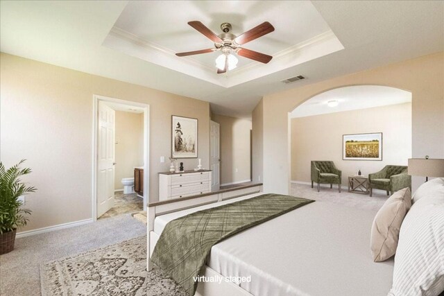 12900 Noche Clara Dr, Del Valle, TX 78617 - carpeted bedroom with arched walkways, a tray ceiling, crown molding, ensuite bathroom, and baseboards