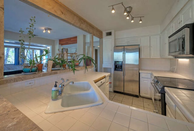 614 Sunfish St, Lakeway, TX 78734 - kitchen featuring stainless steel appliances, a sink, tile countertops, white cabinets, and light tile patterned flooring