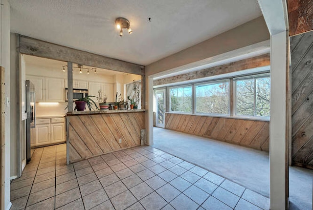614 Sunfish St, Lakeway, TX 78734 - kitchen featuring light colored carpet, stainless steel appliances, wooden walls, rail lighting, and light tile patterned flooring
