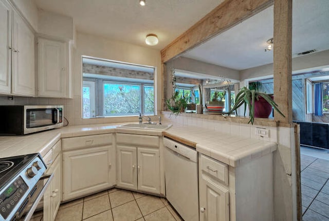 614 Sunfish St, Lakeway, TX 78734 - kitchen with tile countertops, stainless steel appliances, a sink, light tile patterned flooring, and beamed ceiling