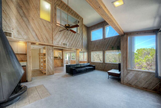 614 Sunfish St, Lakeway, TX 78734 - carpeted living area featuring wood walls, plenty of natural light, ceiling fan, beamed ceiling, and a wood stove