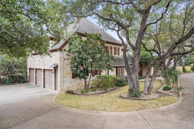 4403 Elohi Dr, Austin, TX 78746 - view of front of property featuring driveway, stone siding, roof with shingles, and an attached garage