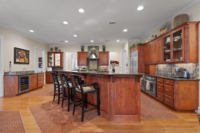 4403 Elohi Dr, Austin, TX 78746 - kitchen with beverage cooler, appliances with stainless steel finishes, wall chimney exhaust hood, a breakfast bar area, and backsplash