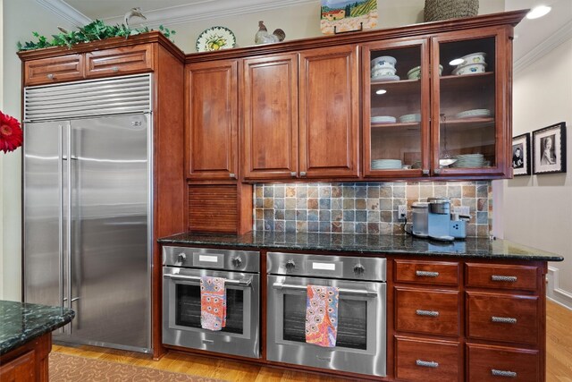 4403 Elohi Dr, Austin, TX 78746 - kitchen with appliances with stainless steel finishes, ornamental molding, backsplash, glass insert cabinets, and dark stone countertops