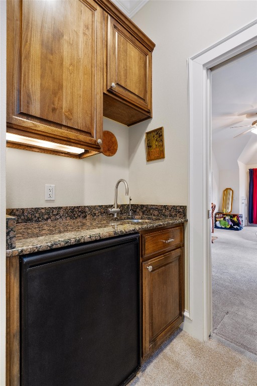 4403 Elohi Dr, Austin, TX 78746 - kitchen with light colored carpet, ceiling fan, dark stone countertops, and brown cabinetry