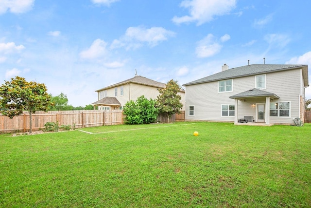back of property with a yard, a chimney, a patio area, and a fenced backyard