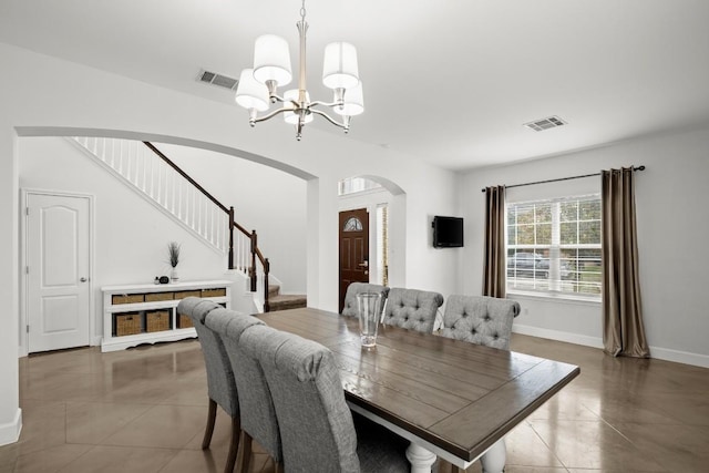 tiled dining room featuring arched walkways, stairs, a notable chandelier, and visible vents