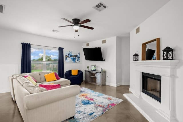 tiled living area with a fireplace with raised hearth, visible vents, and a ceiling fan