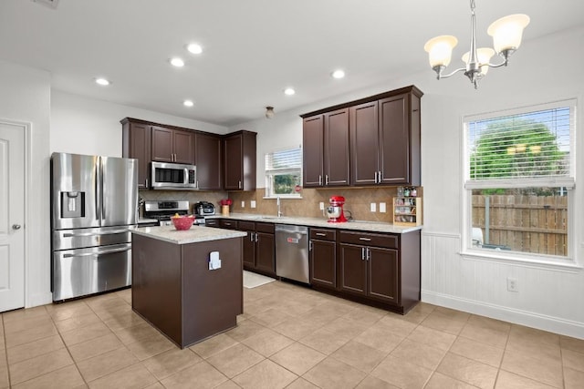 kitchen featuring dark brown cabinetry, stainless steel appliances, tasteful backsplash, and a chandelier