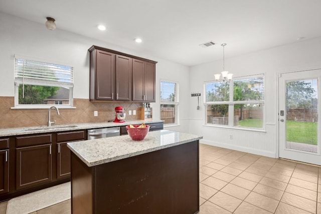 kitchen with a sink, visible vents, dishwasher, backsplash, and a notable chandelier