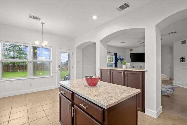 kitchen with light tile patterned floors, hanging light fixtures, visible vents, and arched walkways