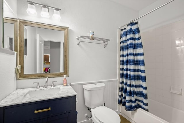 full bathroom featuring vanity, toilet, shower / tub combo, and a wainscoted wall