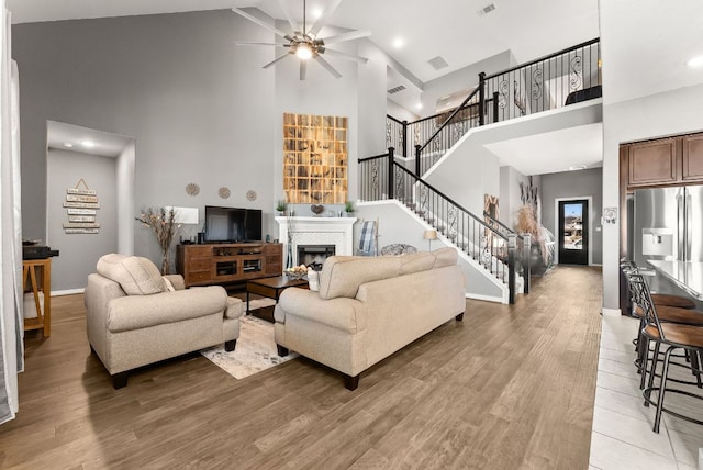 386 Nautical Loop, Kyle, TX 78640 - living area with a towering ceiling, a fireplace, a ceiling fan, stairs, and light wood-style floors