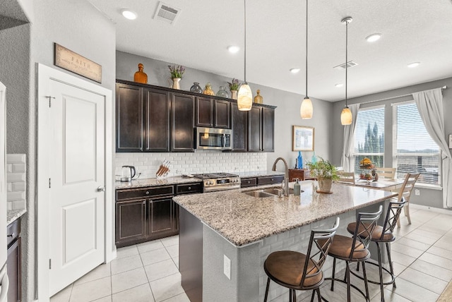386 Nautical Loop, Kyle, TX 78640 - kitchen featuring a sink, stainless steel appliances, light tile patterned flooring, decorative backsplash, and a breakfast bar area