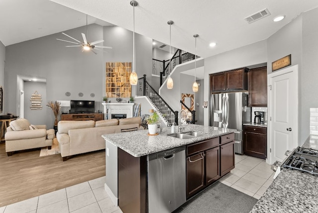386 Nautical Loop, Kyle, TX 78640 - kitchen featuring appliances with stainless steel finishes, high vaulted ceiling, a sink, light tile patterned flooring, and a fireplace