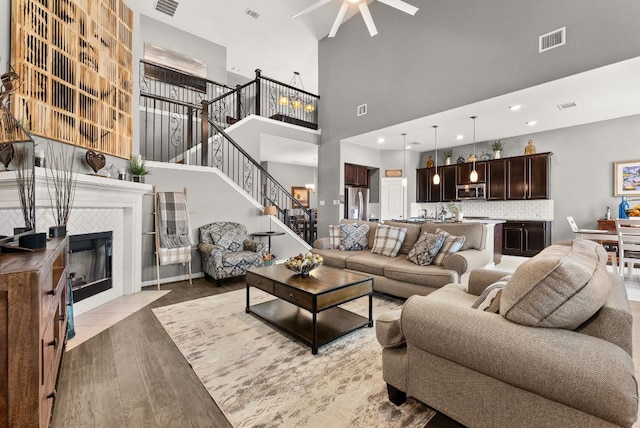 386 Nautical Loop, Kyle, TX 78640 - living area featuring ceiling fan, stairs, light wood-style floors, a towering ceiling, and a tile fireplace
