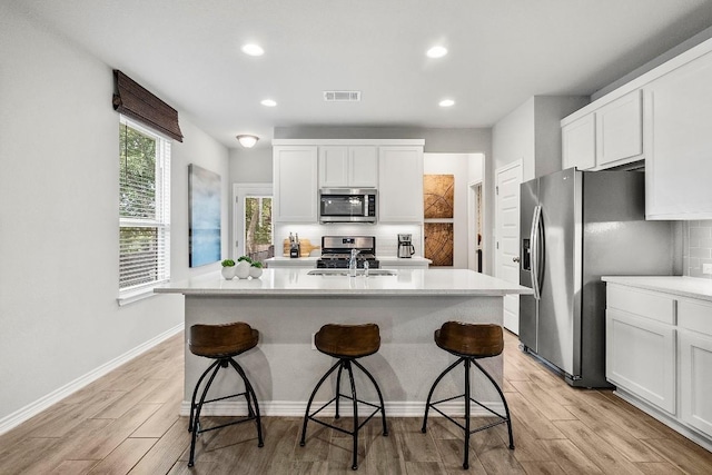 kitchen with visible vents, light countertops, decorative backsplash, stainless steel appliances, and a sink