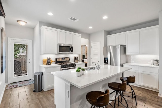kitchen featuring visible vents, a kitchen bar, decorative backsplash, appliances with stainless steel finishes, and a sink