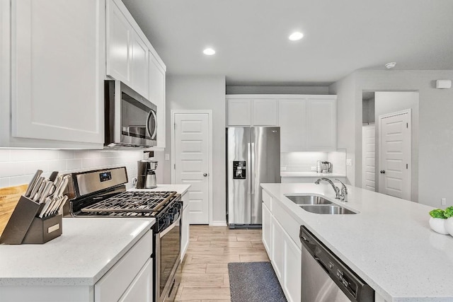 1405 Ambler Dr, Austin, TX 78753 - kitchen featuring appliances with stainless steel finishes, tasteful backsplash, light wood finished floors, white cabinetry, and recessed lighting