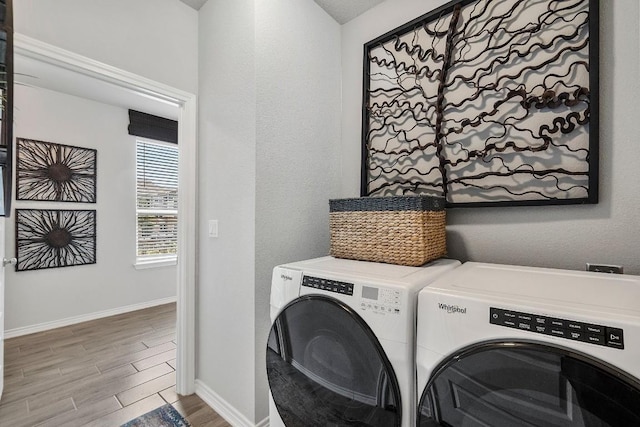 washroom with wood finish floors, baseboards, independent washer and dryer, and laundry area