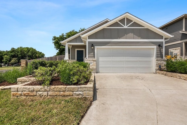 craftsman inspired home featuring fence, driveway, a garage, stone siding, and board and batten siding