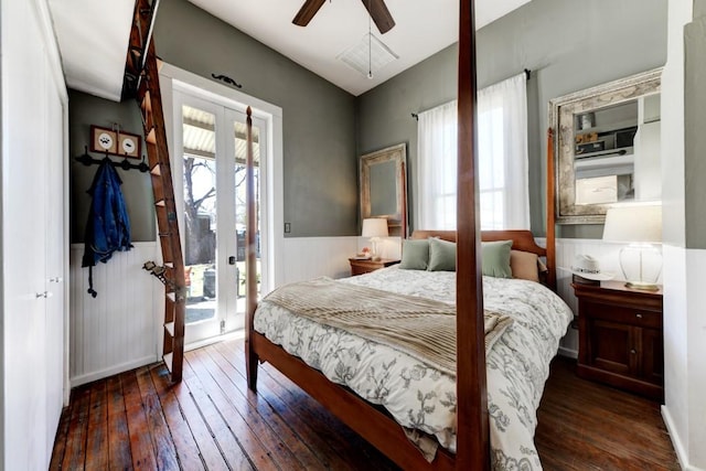 bedroom with french doors, multiple windows, wood-type flooring, wainscoting, and access to outside