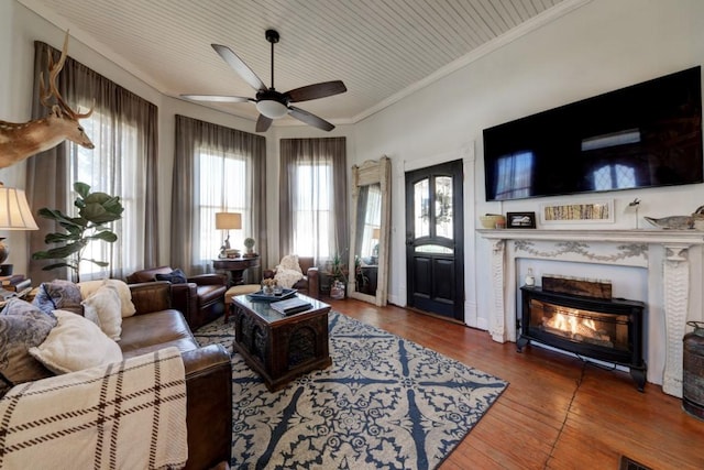 living room featuring ceiling fan, wood-type flooring, crown molding, and a lit fireplace