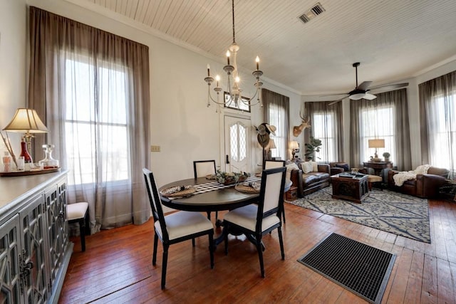dining space with wood-type flooring, ornamental molding, a ceiling fan, and a chandelier
