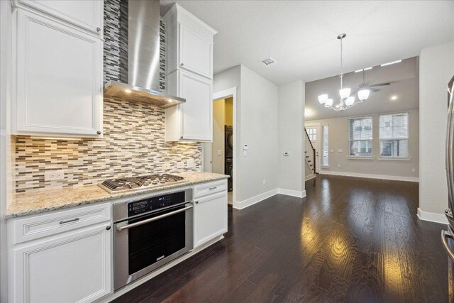 7508 Pantherpaw St, Austin, TX 78757 - kitchen with stainless steel appliances, wall chimney exhaust hood, dark wood-type flooring, and a chandelier