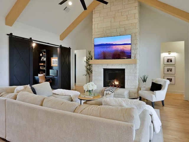871 Blackbuck Ridge Dr, Lampasas, TX 76550 - living area featuring visible vents, beam ceiling, a barn door, a fireplace, and light wood finished floors