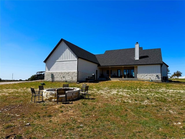 871 Blackbuck Ridge Dr, Lampasas, TX 76550 - rear view of house featuring a lawn, board and batten siding, stone siding, and an outdoor fire pit