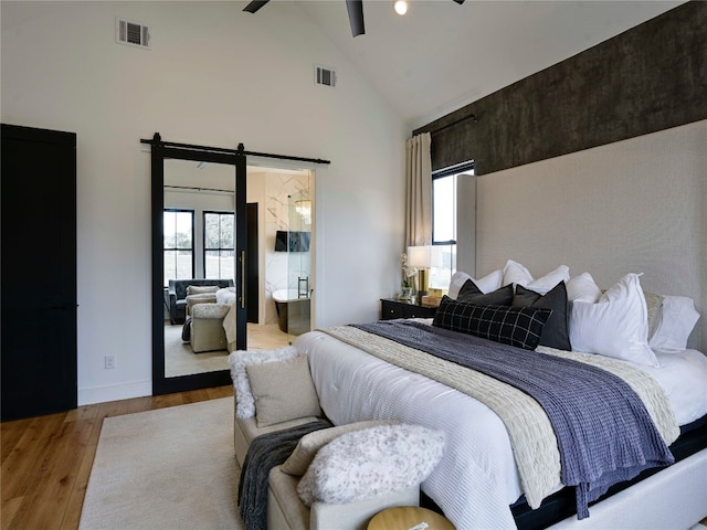 871 Blackbuck Ridge Dr, Lampasas, TX 76550 - bedroom with a barn door, wood finished floors, visible vents, and high vaulted ceiling