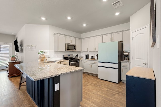 321 Cherry Laurel Ln, Kyle, TX 78640 - kitchen featuring appliances with stainless steel finishes, a sink, a peninsula, a kitchen bar, and visible vents