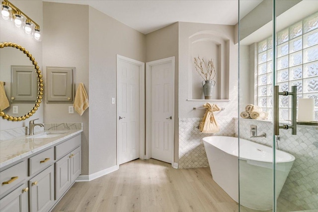 9201 Cessna Ln, Austin, TX 78717 - bathroom with wood finished floors, vanity, a soaking tub, and tile walls
