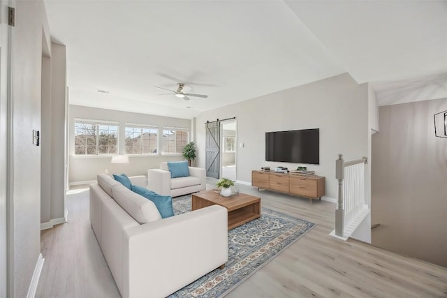 9201 Cessna Ln, Austin, TX 78717 - living room with a barn door, light wood-type flooring, ceiling fan, and baseboards