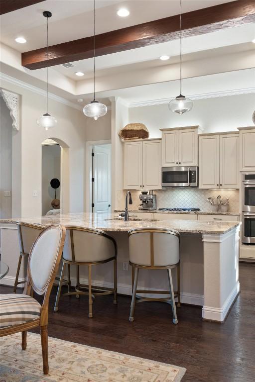 9525 Stratus Dr, Dripping Springs, TX 78620 - kitchen featuring appliances with stainless steel finishes, recessed lighting, tasteful backsplash, light stone countertops, and a kitchen bar