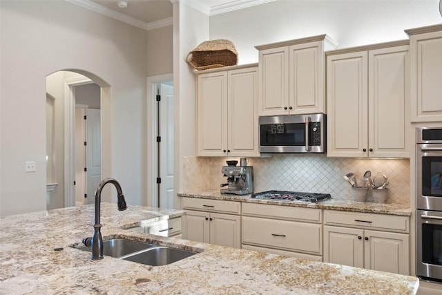 9525 Stratus Dr, Dripping Springs, TX 78620 - kitchen with stainless steel appliances, a sink, arched walkways, backsplash, and ornamental molding
