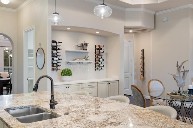 9525 Stratus Dr, Dripping Springs, TX 78620 - kitchen with a sink, ornamental molding, hanging light fixtures, light stone countertops, and arched walkways