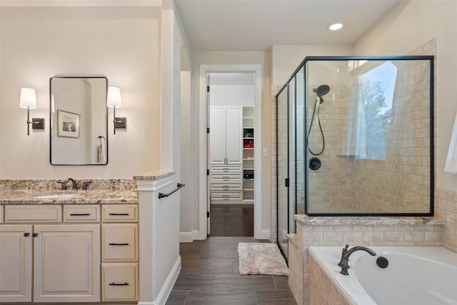 9525 Stratus Dr, Dripping Springs, TX 78620 - bathroom featuring a stall shower, a walk in closet, a garden tub, vanity, and baseboards