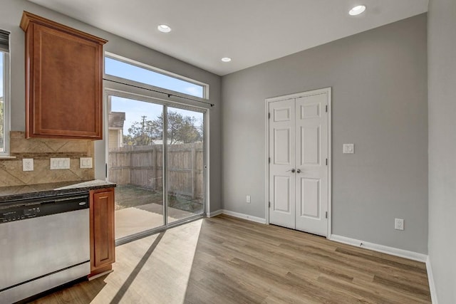 512 Eberhart Ln Unit 1207, Austin, TX 78745 - kitchen with stainless steel dishwasher, dark countertops, light wood-type flooring, baseboards, and decorative backsplash