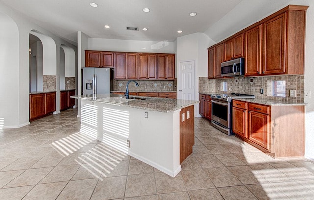 120 Mountain Laurel Way, Austin, TX 78737 - kitchen featuring appliances with stainless steel finishes, a sink, light tile patterned floors, arched walkways, and light stone counters