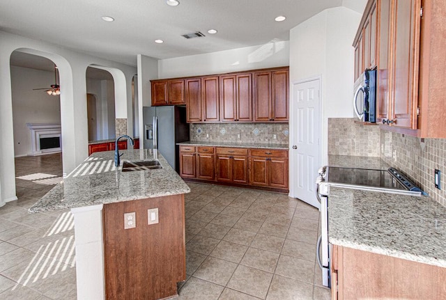 120 Mountain Laurel Way, Austin, TX 78737 - kitchen featuring appliances with stainless steel finishes, arched walkways, tasteful backsplash, recessed lighting, and brown cabinets