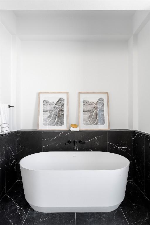106 Bella Montagna Cir, Austin, TX 78734 - full bath featuring tile walls, a freestanding bath, a wainscoted wall, and marble finish flooring