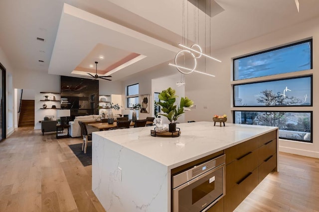 106 Bella Montagna Cir, Austin, TX 78734 - kitchen featuring stainless steel microwave, modern cabinets, a raised ceiling, hanging light fixtures, and light wood finished floors