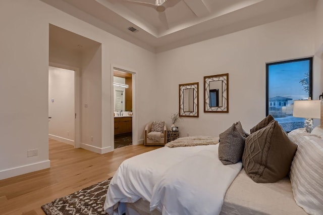 106 Bella Montagna Cir, Austin, TX 78734 - bedroom featuring light wood-type flooring, connected bathroom, and a tray ceiling