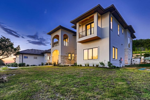 106 Bella Montagna Cir, Austin, TX 78734 - view of front of house with stucco siding, stone siding, a lawn, and a balcony