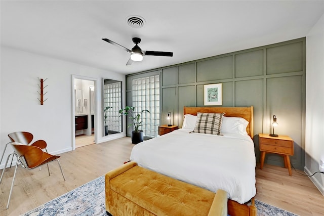 1205 Westmoor Dr, Austin, TX 78723 - bedroom with a decorative wall, baseboards, light wood-style floors, ensuite bath, and ceiling fan
