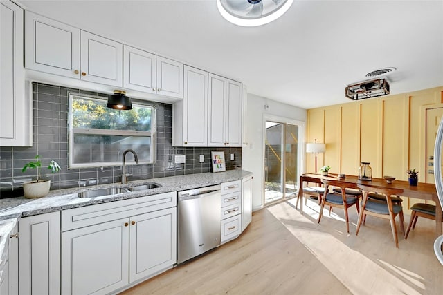 1205 Westmoor Dr, Austin, TX 78723 - kitchen with stainless steel dishwasher, a sink, backsplash, light wood-type flooring, and light stone countertops