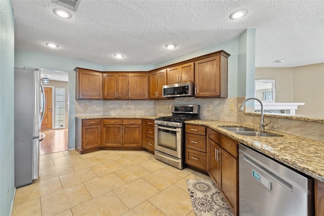 2103 Heather Dr, Cedar Park, TX 78613 - kitchen with stainless steel appliances, brown cabinetry, decorative backsplash, light stone countertops, and a textured ceiling